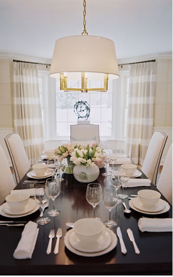 Formal dining room with dark wood table, upholstered white chairs and striped beige and white curtains