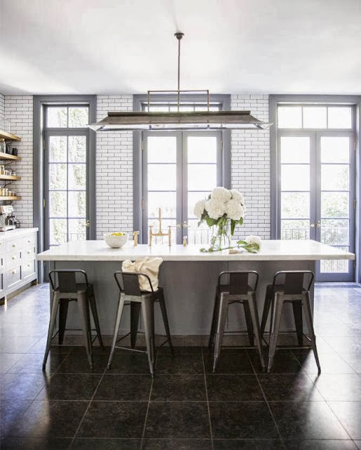Kitchen in a West Village apartment with subway with dark grout walls, grey cabinets, French doors and large kitchen island