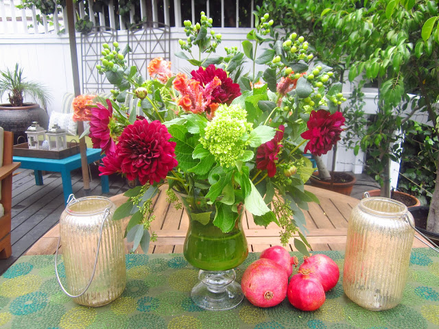completed flower arrangement with 4 pomegranates on a wooden patio table