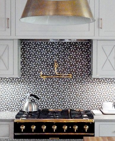 Kitchen with white cabinet and drawers, black appliances with brass accents and a pinwheel tile backsplash