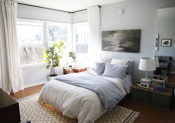 Bedroom before makeover grey walls wood floor blue and grey bedding