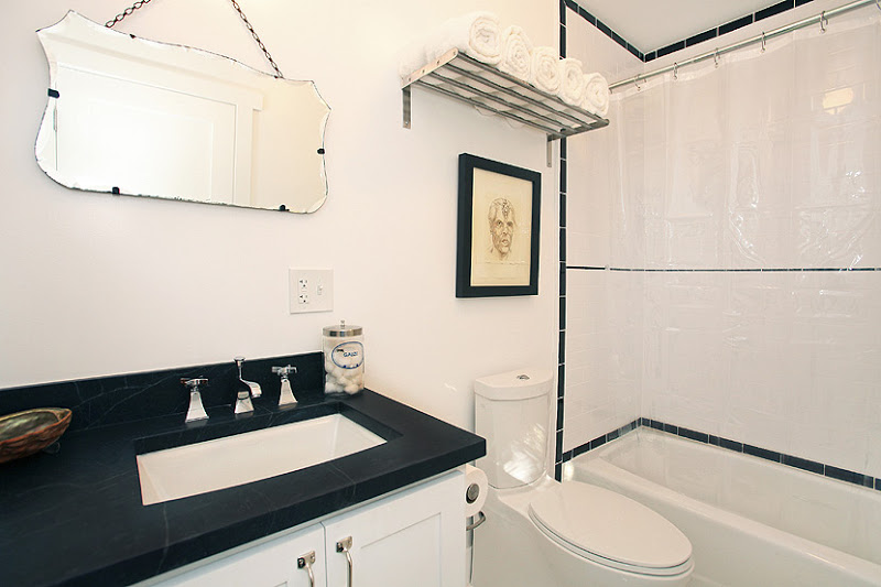 Master bathroom with white cabinets, black counter top and white subway tiles in the shower with a black tile trim