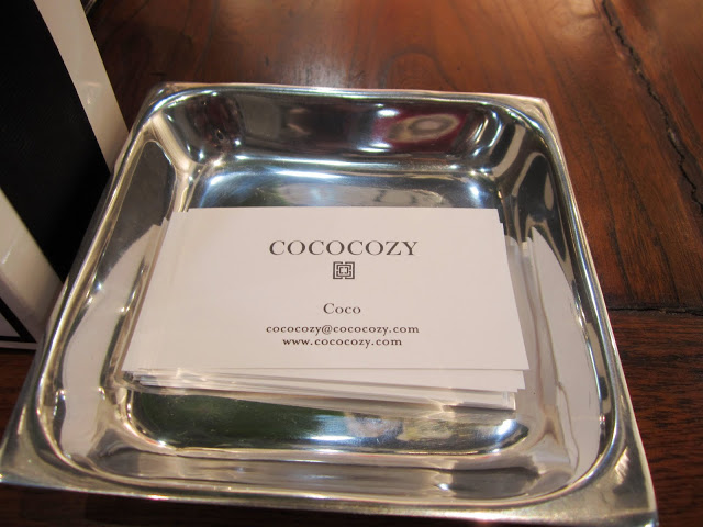 Coco's card in a silver dish on a wood table at the COCOCOZY booth during the New York International Gift Fair