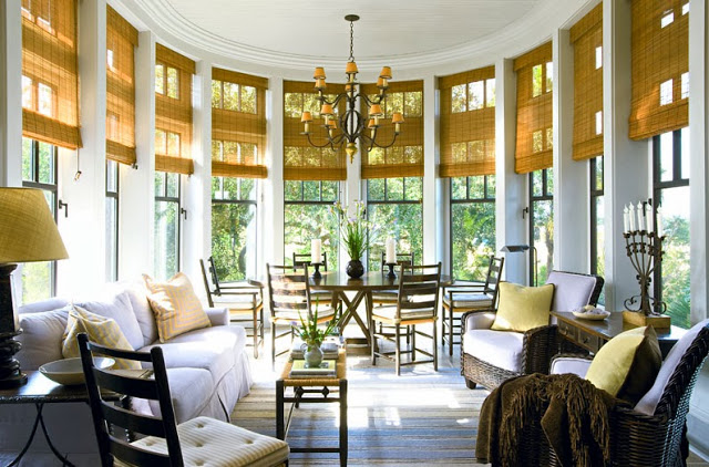 Informal dining room in a South Carolina estate with woven shades, rattan arm chairs, and a white sofa