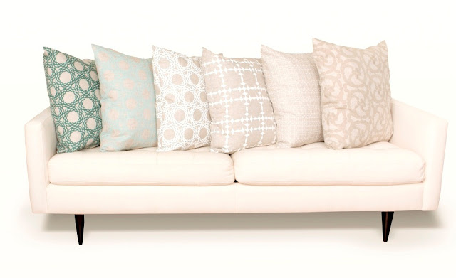 Six COCOCOZY pillows in different colors and patterns on a white sofa