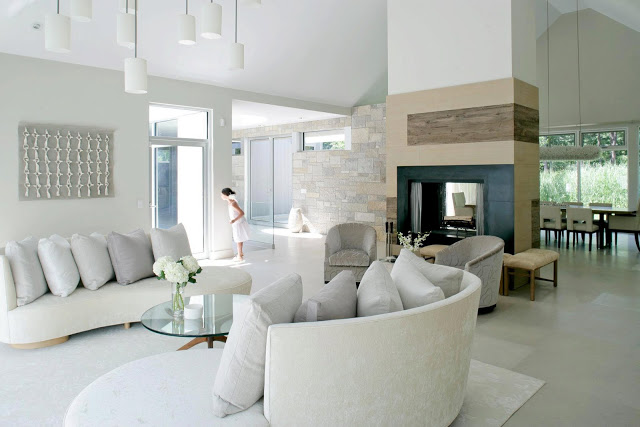 Living room in a white, modern farmhouse with a fireplace, dueling white sofas and white pendant lights