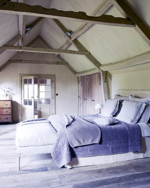 country chic bedroom with reclaimed wood floor, high ceiling, visible beams, and a simple rustic chest of drawers