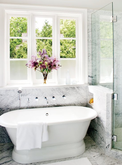 bathroom with stand in tub, marble floors and a large encasement window