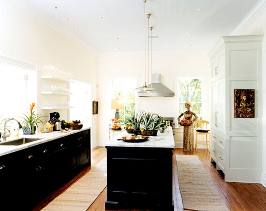 Kitchen with jet black lower cabinets, marble countertops, floating shelves instead of upper cabinets and pendant lights