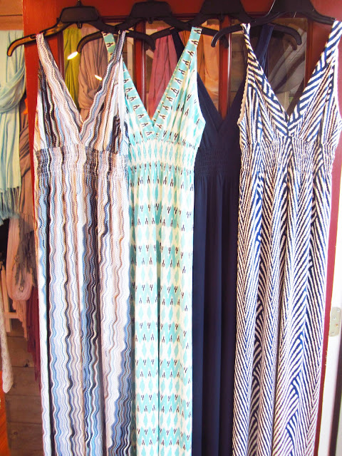 Four summer maxi dresses hanging from black hangers
