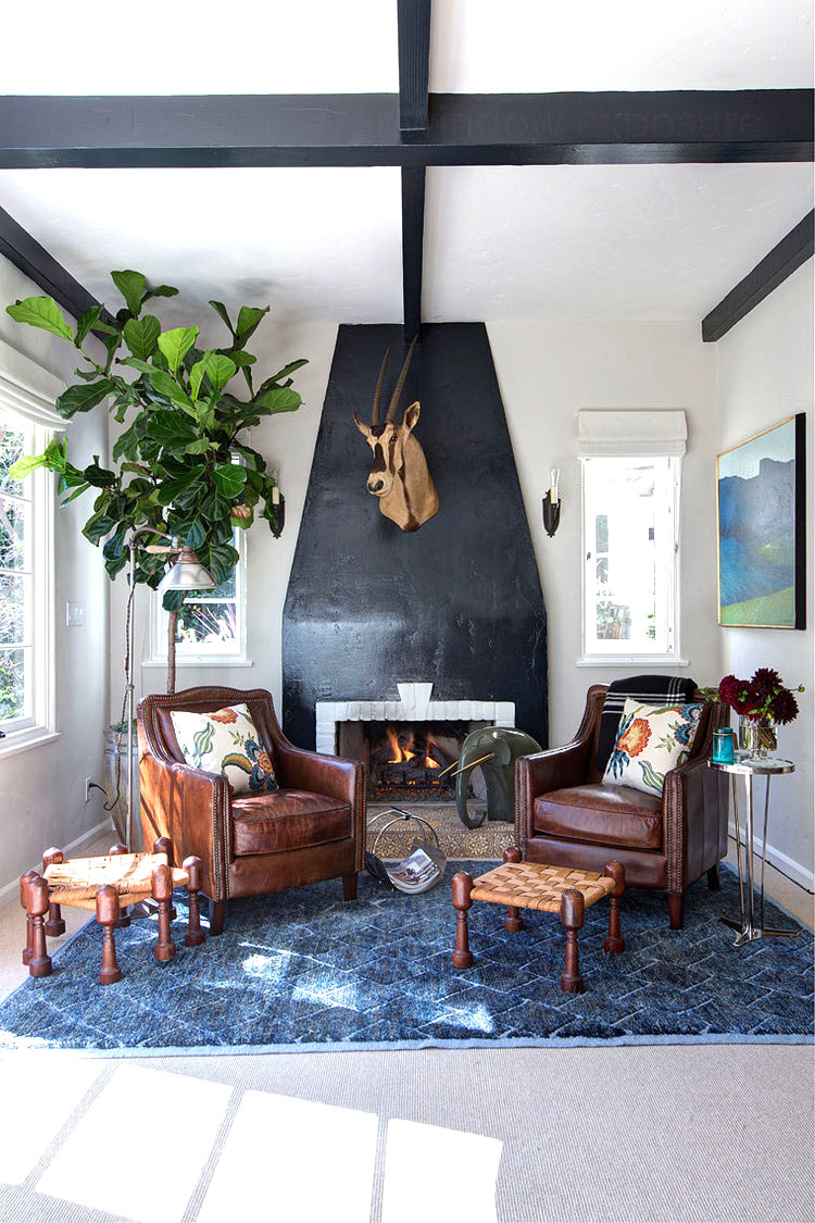 Den with leather armchairs, black fireplace and an antelope head