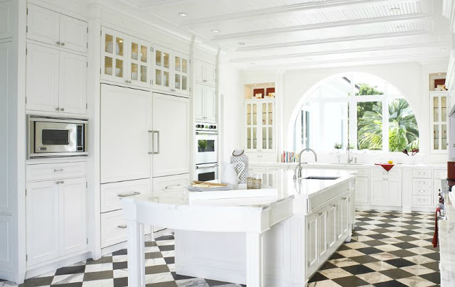 All white kitchen with checkered marble floor and an arched window