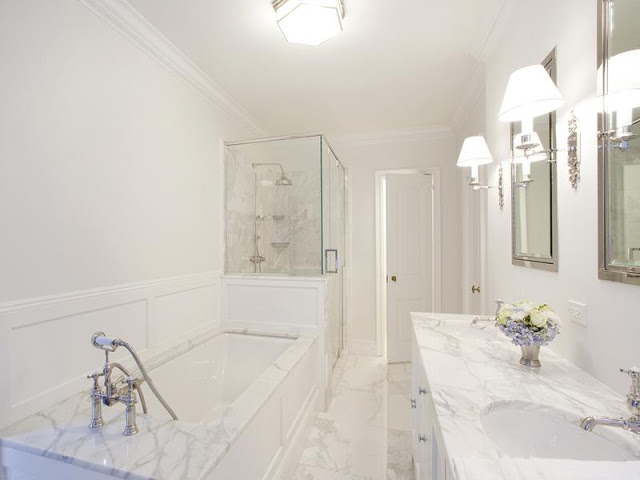 master bathroom with marble drop in tub and counter tops and a clear glass enclosed shower