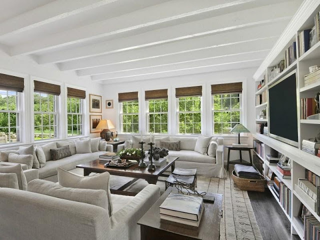 Grey living room in an East Hampton compound with stained wood floor, built in bookcase and painted ceiling beams