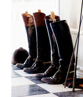 row of peter se carlsson riding boots in a mudroom foyer with checkered floors