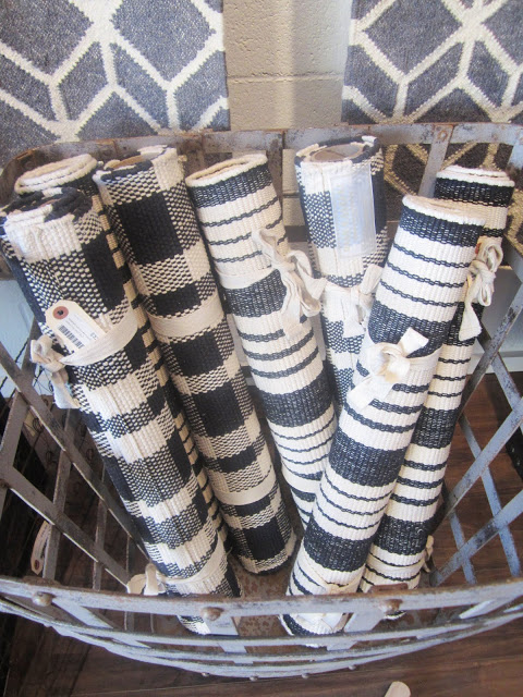  flat weave cotton rugs in navy and white plaids and stripes rolled up in a metal hamper