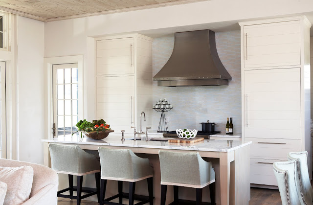 kitchen in a beach house with white cabinets, an island with marble countertop, and small subway tile backsplash