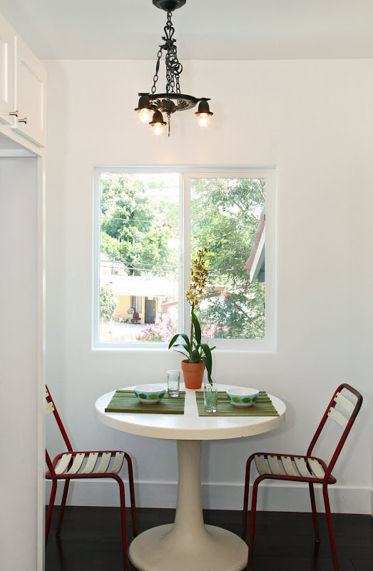 Breakfast nook in a Spanish Style home with two red chairs, a round white table and Koa wood floor