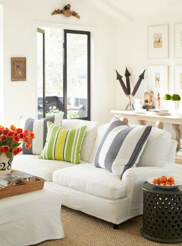 close up of white sofas with striped accent pillows and black trimmed windows