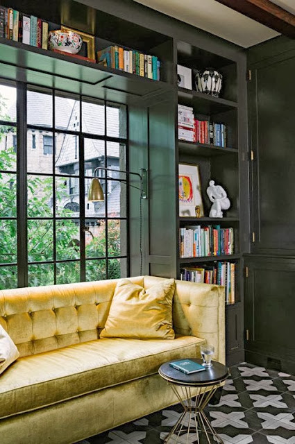 Gold velvet tufted sofa in a window nook in a modern kitchen with built in bookshelves