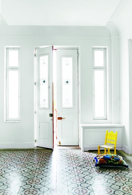 white entry way with tiles and a child's chair