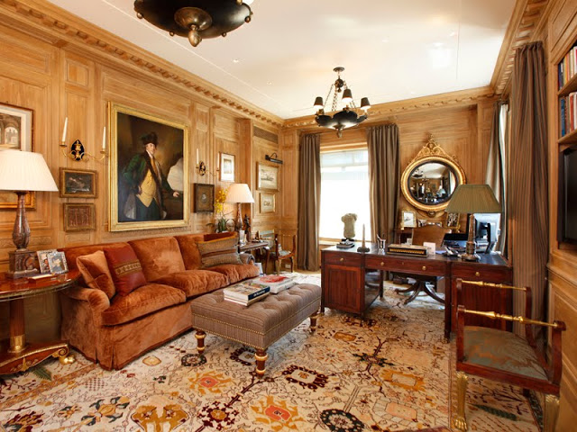 Home office with molded walls, large area rug, upholstered sofa, ottoman and chandelier 