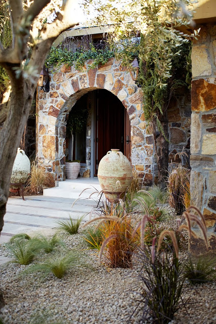 exterior of napa showhouse front door with stone arch and desert plants