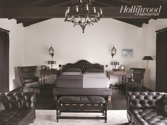 master bedroom with a tufted headboard, ottoman, dueling sofas, two arm chairs, a chandelier and exposed beams