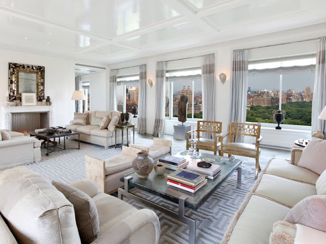 Alternative view of the living room showing it's many windows looking over Central Park, fireplace, and dueling sofas 