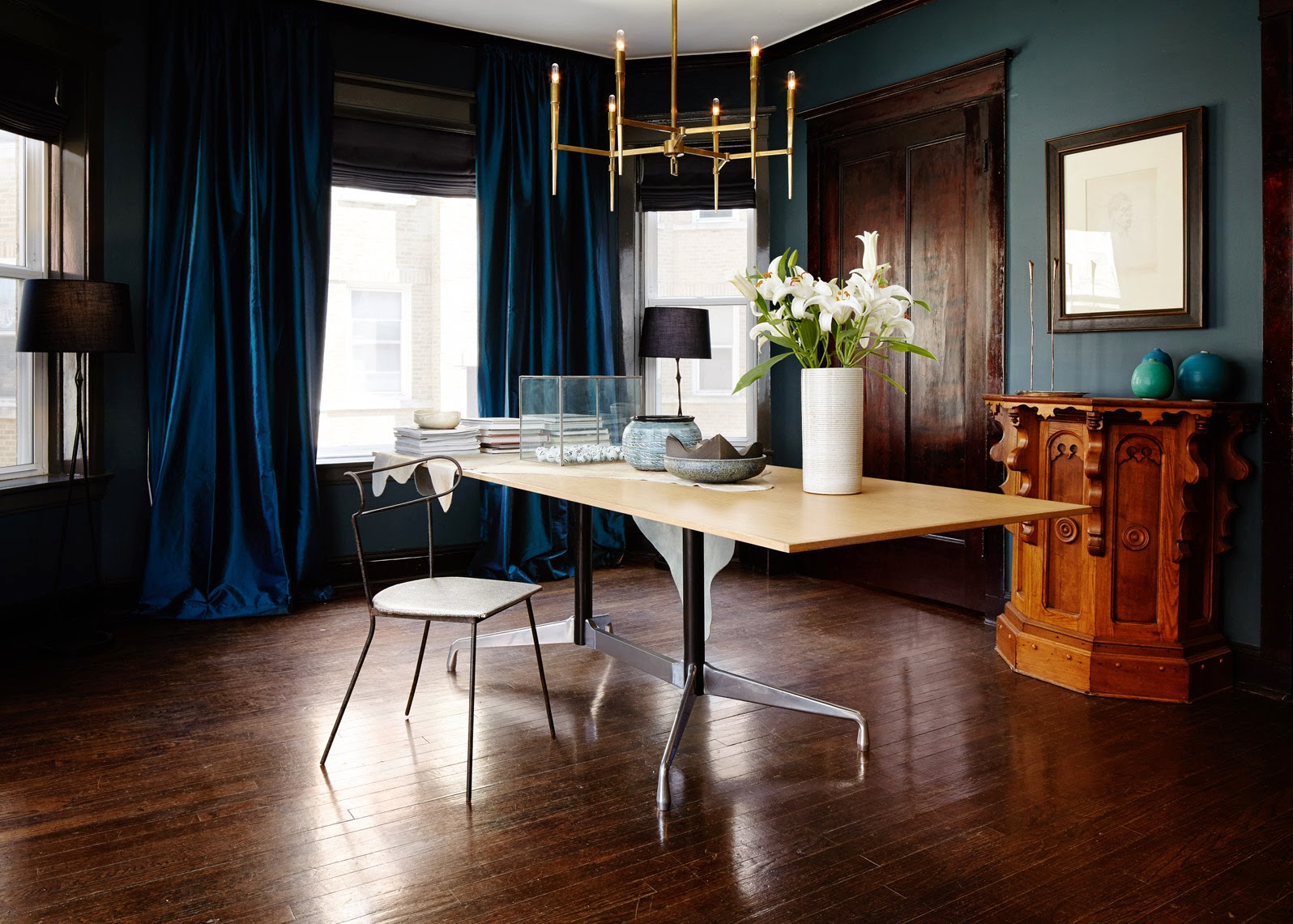 Simple dining room with brass chandelier and blue curtains