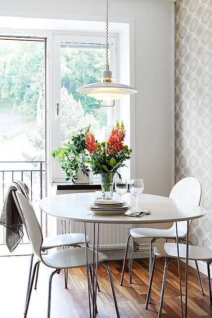 Breakfast nook in a small kitchen with a round white table, four chairs and a cute flower arrangement 