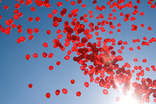 a bunch of red balloons being released into a blue sky