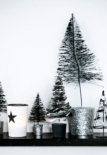 close up of black, white and silver line klein holiday display on a fireplace mantel with silver miniature christmas trees and candles