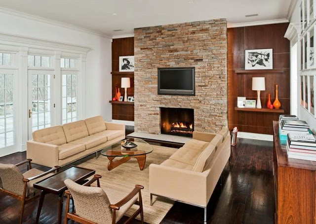 Den in a mansion with a mid century modern vibe with a stone fireplace, a Noguchi coffee table, dueling sofas, and a wall mounted TV