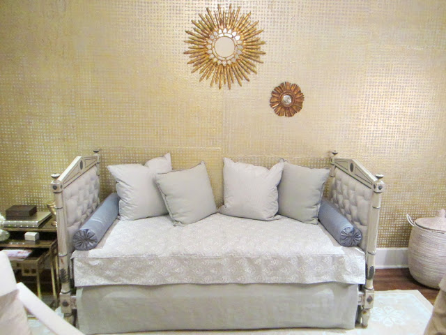 Upholstered day bed in the House of Windor's baby room with gold covering by Kneedler-Fauchere and two gold sunburst mirrors