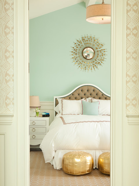 bedroom with mint walls and gold Moroccan poufs at the end of the bed, molded tufted headboard, and vintage nightstand