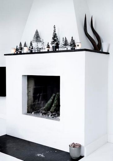 black, white and silver line klein holiday display with a fireplace, on the mantel there are silver miniature christmas trees and candles