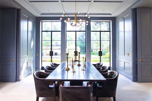 formal dining room with steel painted paneled walls, white coffered ceilings and brass accents
