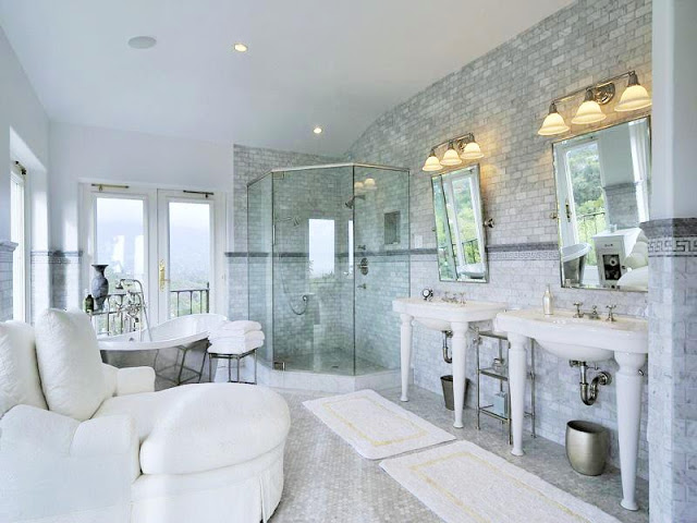 Master bathroom with cararra marble walls, penny round mosaic tile floor, two pedestal sinks, a stand alone tub and large windows
