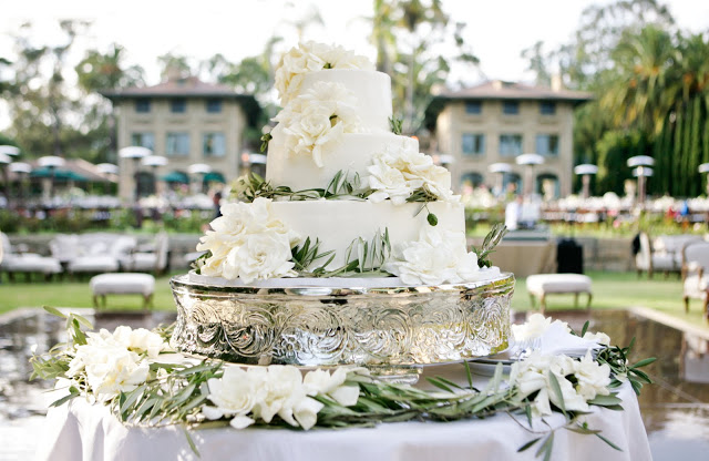 Beautiful three layer wedding cake with flowers on a mercury cake stand