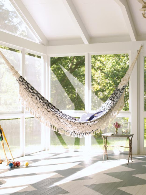 Sun room with floor to ceiling glass windows, Chevron pattern painted on the wood floor and an indoor Lovely hammock