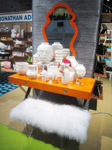 Jonathan Adler's Channing Desk in orange lacquer with white sculptures of Buddhas in front of a large orange mirror 