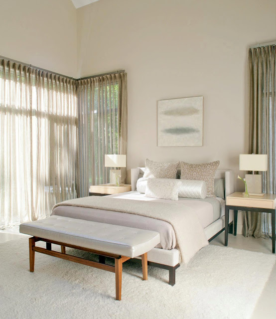Master bedroom in a modern farmhouse with sheer, floor length curtains, two night stands and an ottoman