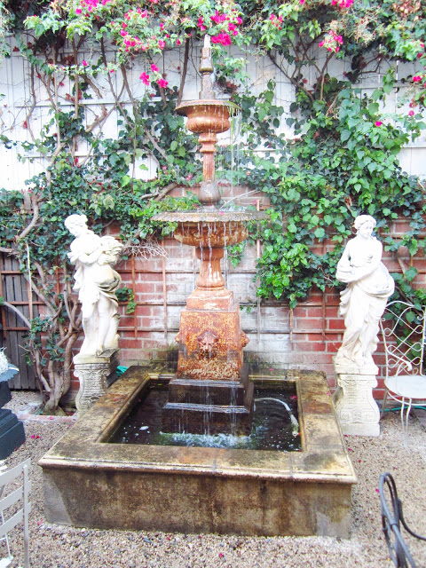 garden fountain in Pom Pom's front courtyard with statues and crushed gravel paving