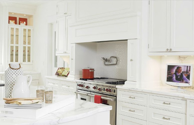 Alternative view of an all white kitchen where you can see the stainless appliances and the subway tile backsplash