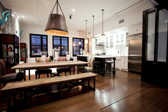 Dining room in Daniel Lowe's Hollywood loft with large bucket inspired pendant light, a rustic industrial wood table and striped chairs and a long bench on one side