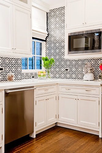 kitchen with white cabinets and drawers, stainless appliances and black and white tile walls