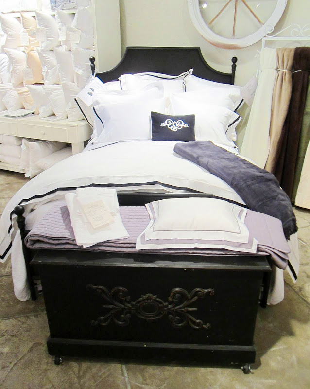 Elegant dark wood bed frame with white bedding with black trim from Downtown Company