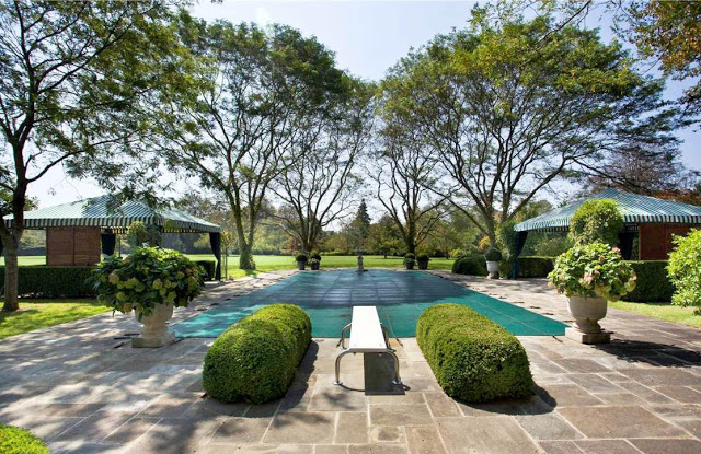 Mansion's backyard with an outdoor pool and diving board
