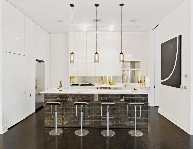 modern kitchen in a Soho Condo in New York with white walls, pendant lights and a brick island
